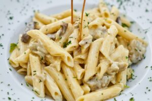 Top 10 Best Foods in the World You Must Try Close-up of creamy pasta with herbs, offering a delicious Italian meal.