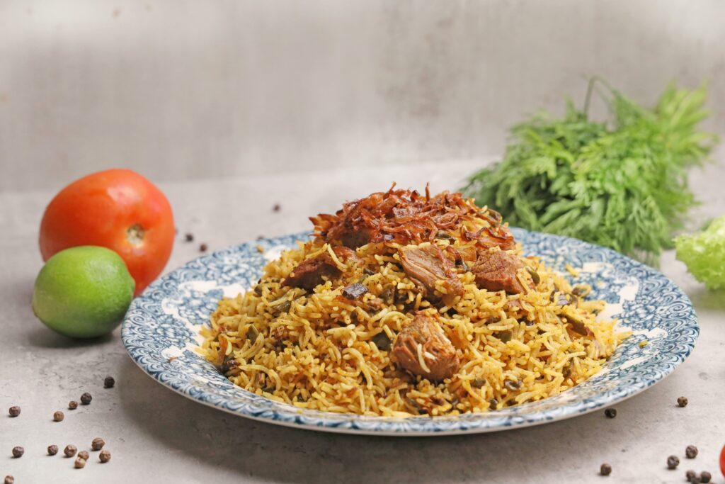 Savor the rich flavors of Indian biryani with succulent lamb on a decorative plate, complemented by fresh vegetables.