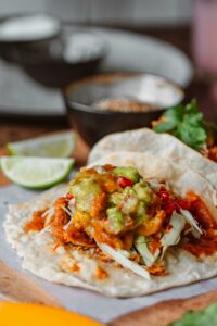 Top 10 Best Foods in the World You Must Try Delicious homemade tacos topped with fresh guacamole, served with lime slices for an authentic Mexican experience.